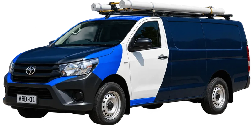 A licensed Seven Hills plumbing van loaded with pipe on the roof rack